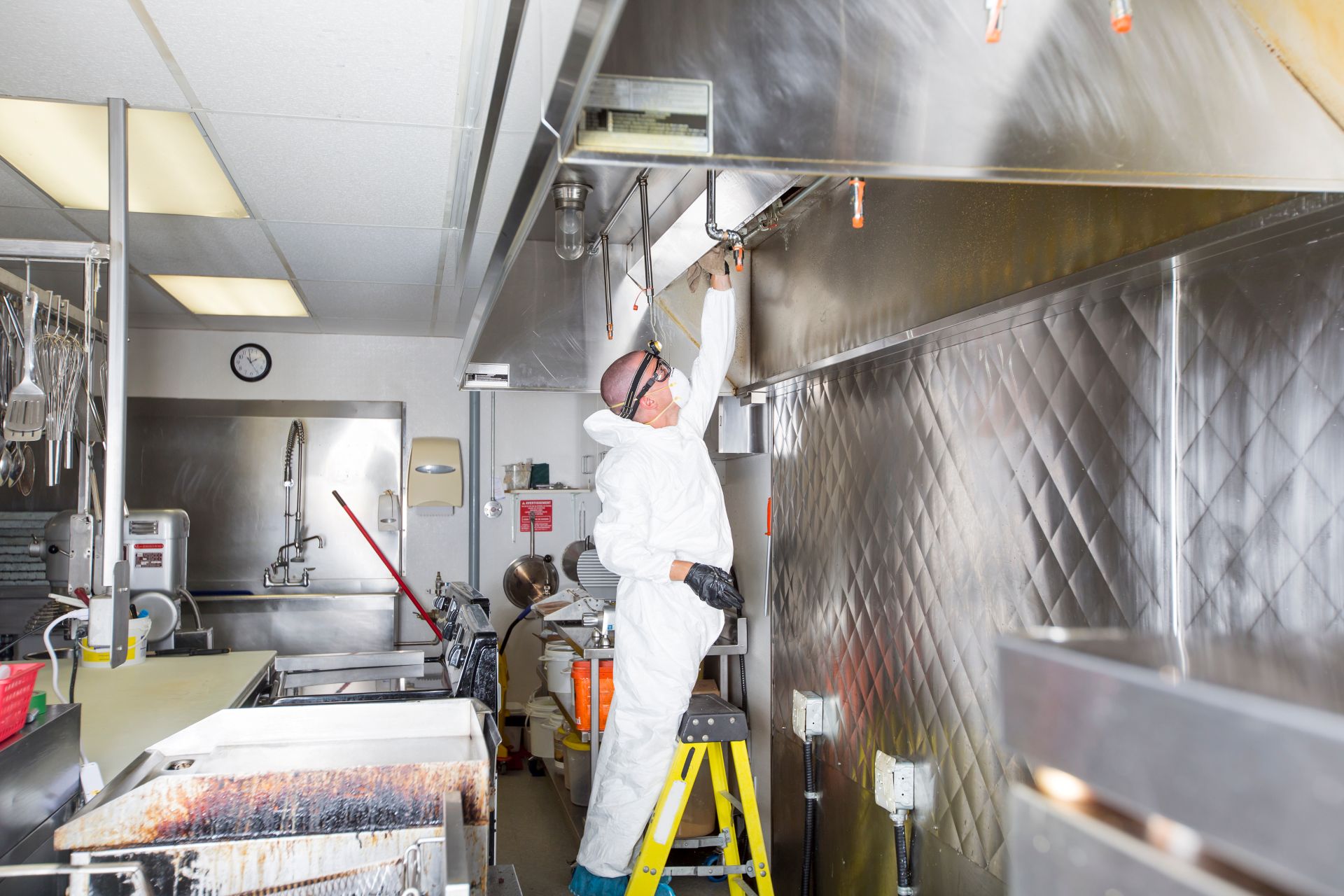 Commercial kitchen worker washing up at sink in professional kitchen
