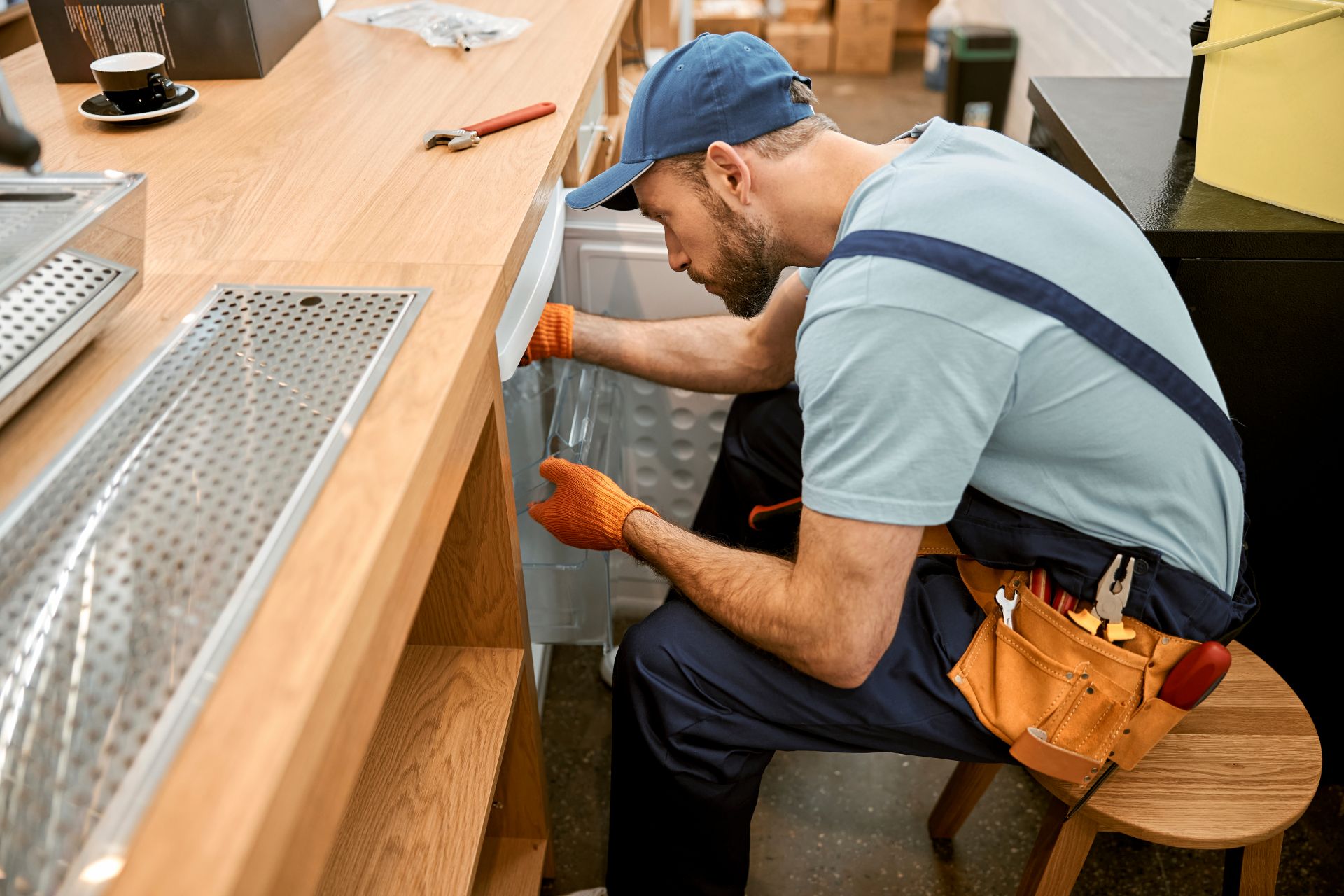 Technician repairing fridge in cafe